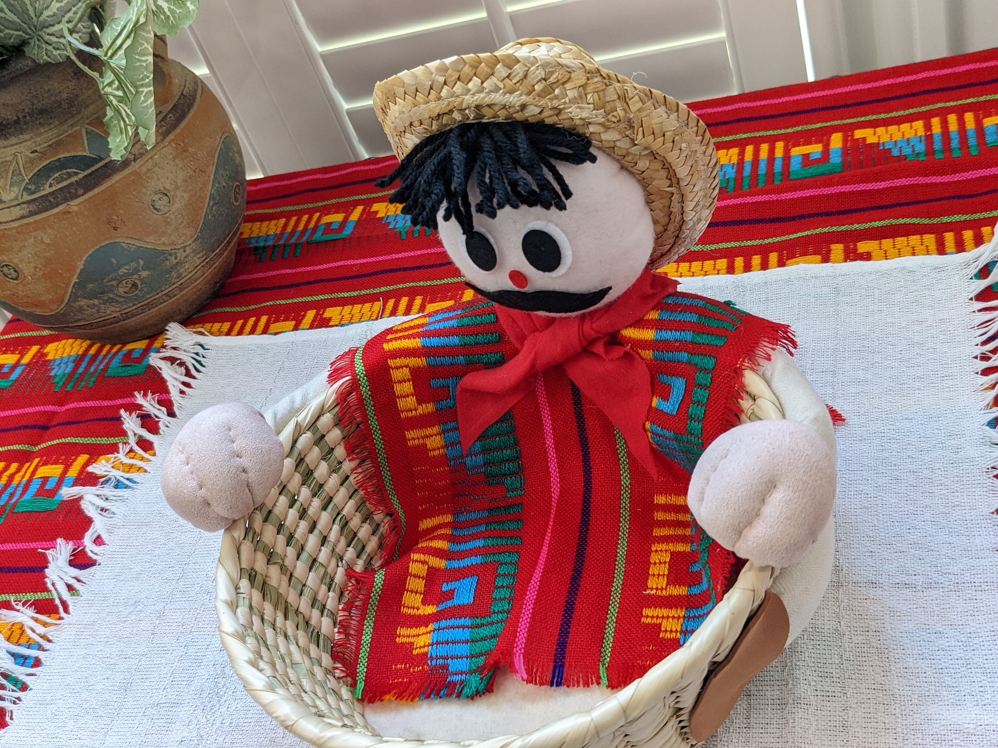 Modeled after our Gabo character, this large tortilla warmer will grab the attention of your guests. With its high capacity palm basket  it can hold at least 30 corn tortillas or at least 20 regular size flour tortillas. Perfect for serving rolls, bread, crackers, or fruit too. Gabo is wearing a colorful poncho made with authentic cambaya fabric. Special gift for taco lovers, kitchen decor or storage.  Gabo 0002 Front